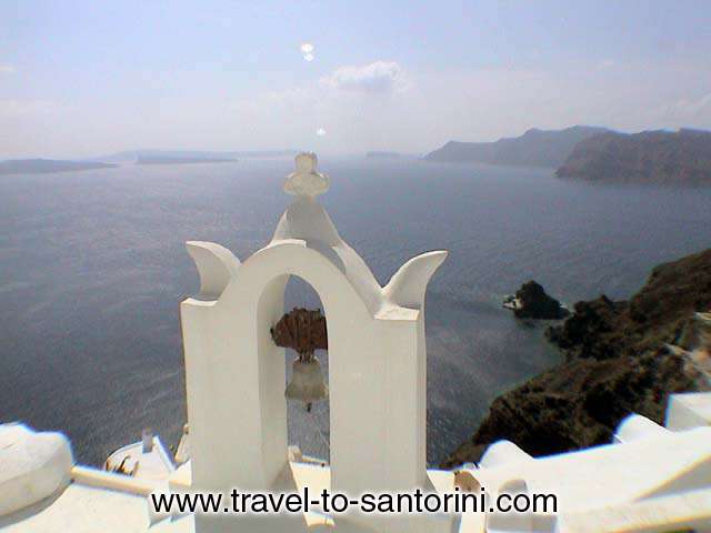 CHURCH BELL - A church bell in Oia and the view of the caldera, the Kameni islands,  Thirassia and the small islet with Agios Nikolaos church.