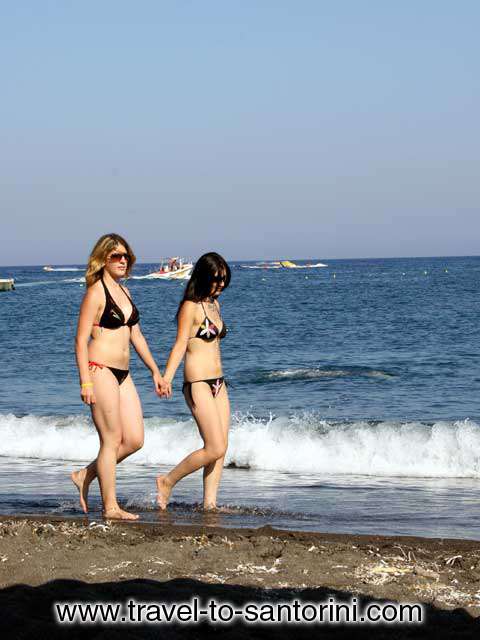 GIRLS - Two girls walking on the beach of Agios Georgios in Santorini