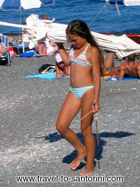 KAMARI BEACH - Girl with umbrella on Kamari beach, Santorini island by Ioannis Matrozos