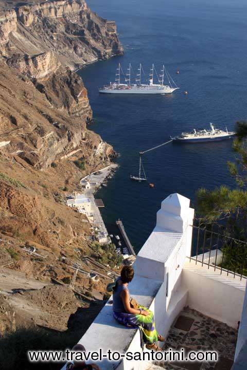 WOMAN WATCHING CALDERA - A woman at the edge of Caldera watching two cruise ships in Gialos