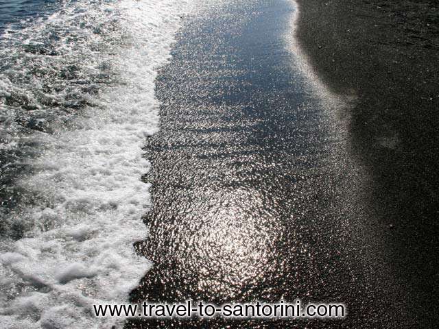 GREY SAND - The dark grey sand of Perivolos beach. While smooth it don't stick on the skin.