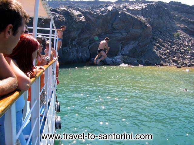 MAN JUMPING - A man jumping in the sea from the boats at the hot springs in Palea Kameni