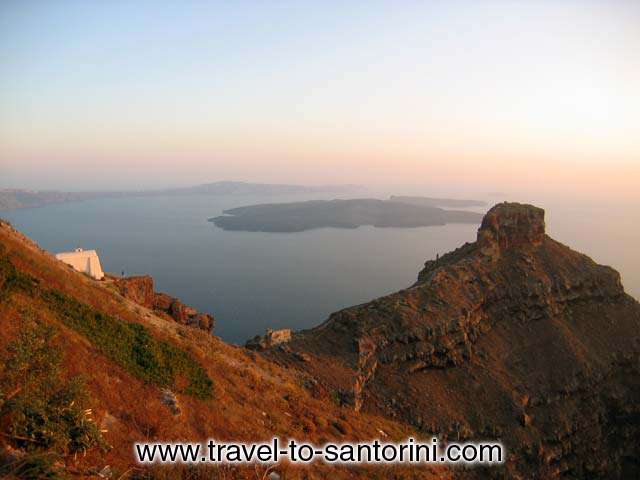 Skaros and volcano view - View of Skaros and the volcano from Imerovigli. On the left a person standing in front of Agios Giannis church.